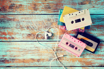 Bunte Musikkassetten mit weißen Kopfhörern auf Holzlatten 